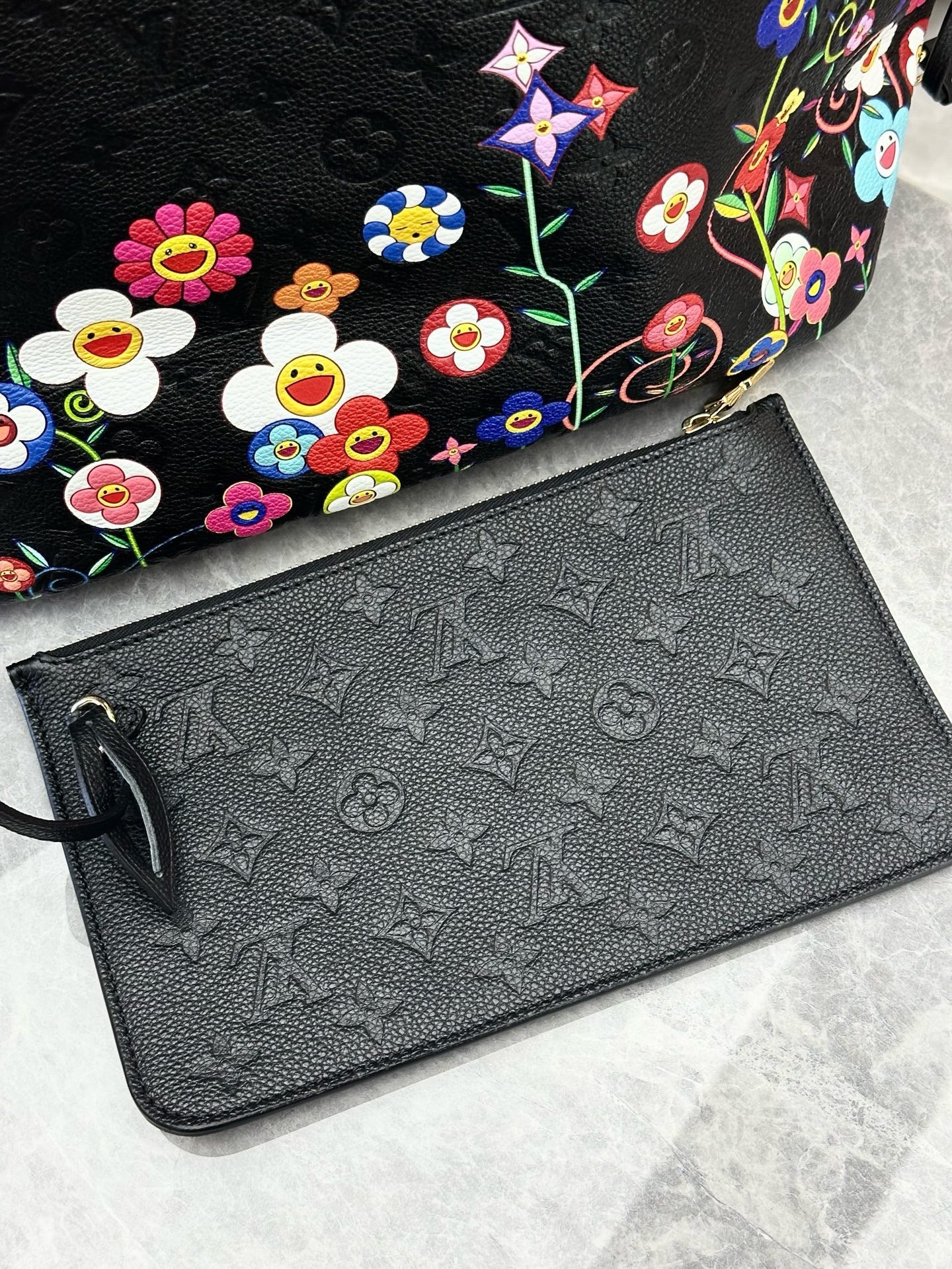 Louis Vuitton x Takashi Murakami Neverfull MM is crafted from black Monogram Empreinte leather and features a vibrant, multicolored floral print