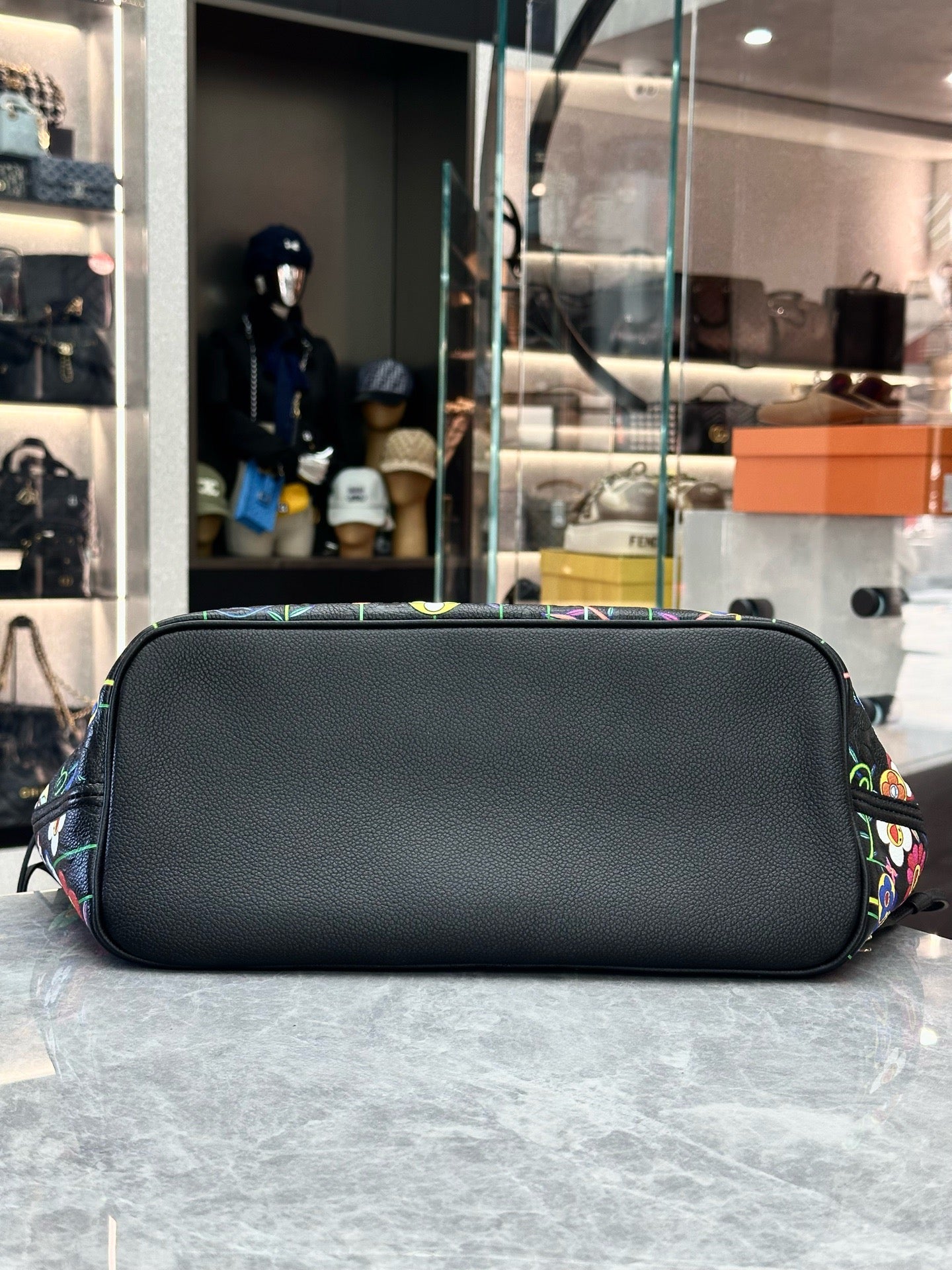 Louis Vuitton x Takashi Murakami Neverfull MM is crafted from black Monogram Empreinte leather and features a vibrant, multicolored floral print