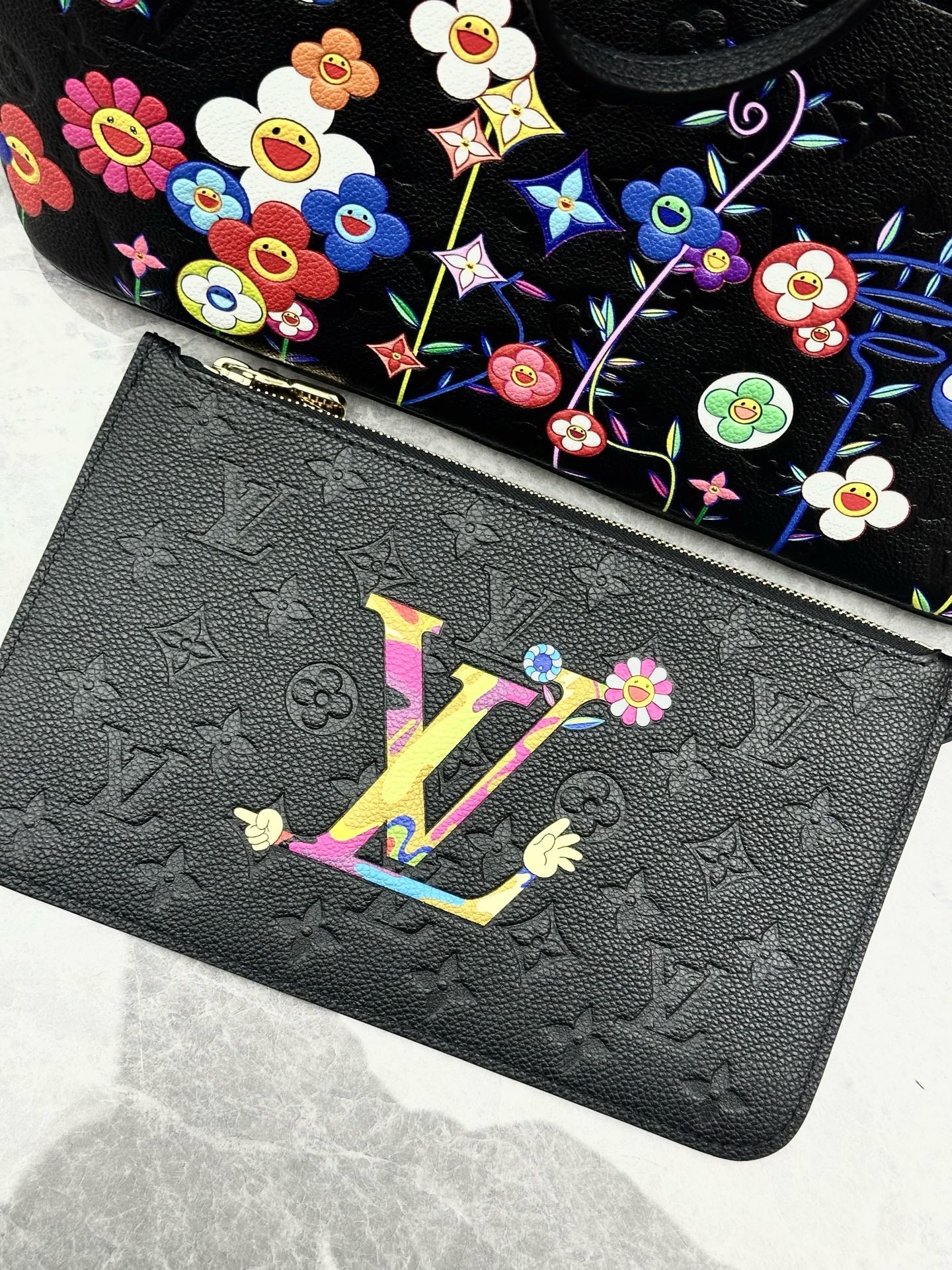Louis Vuitton x Takashi Murakami Neverfull MM is crafted from black Monogram Empreinte leather and features a vibrant, multicolored floral print