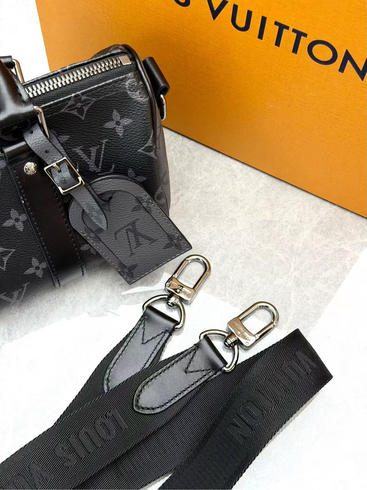 Louis Vuitton Keepall Bandoulière 25 in Monogram Eclipse canvas features black leather trim and silver-tone hardware