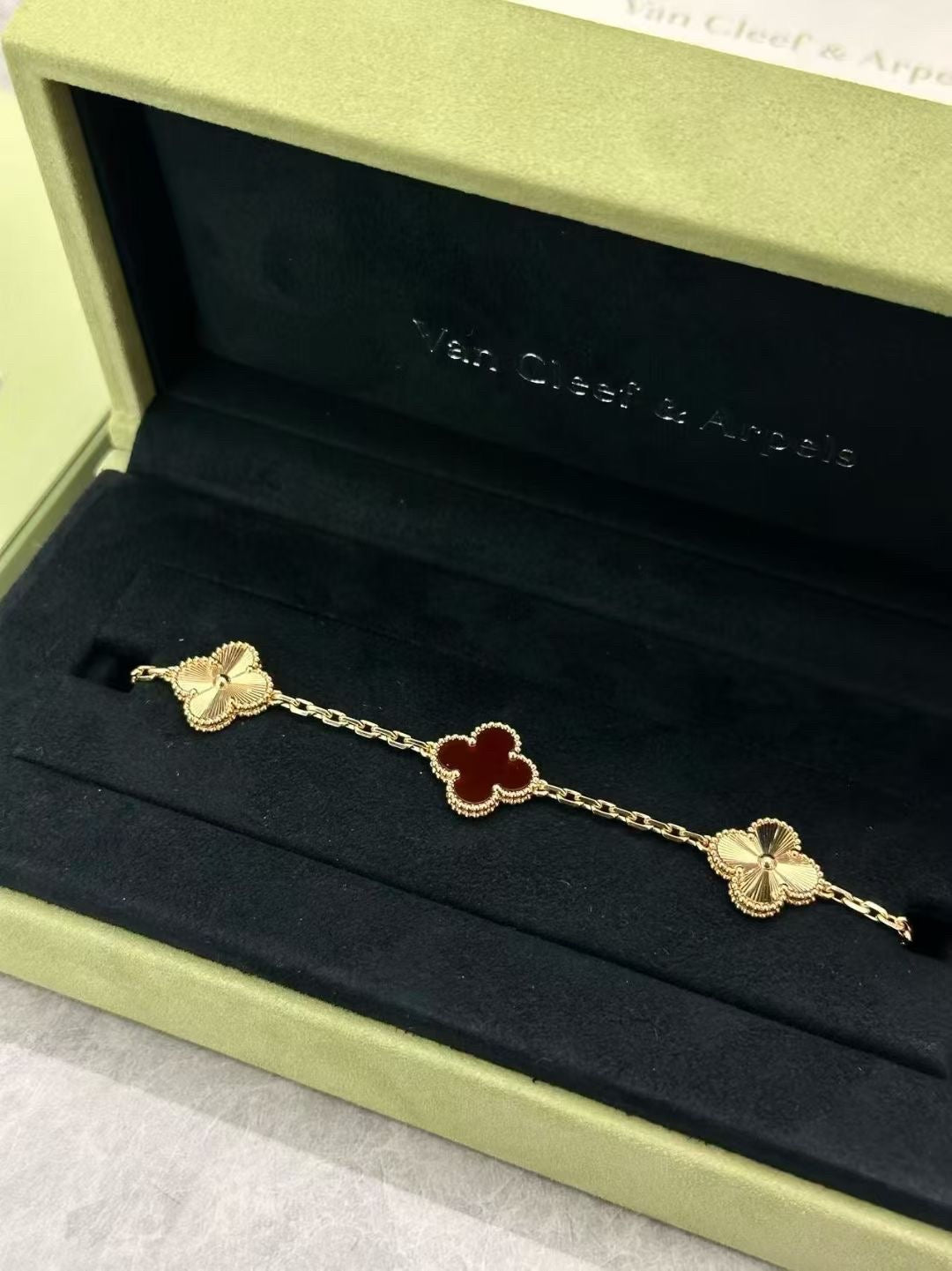 Van Cleef & Arpels Vintage Alhambra bracelet features a central carnelian motif flanked by guilloché yellow gold clovers