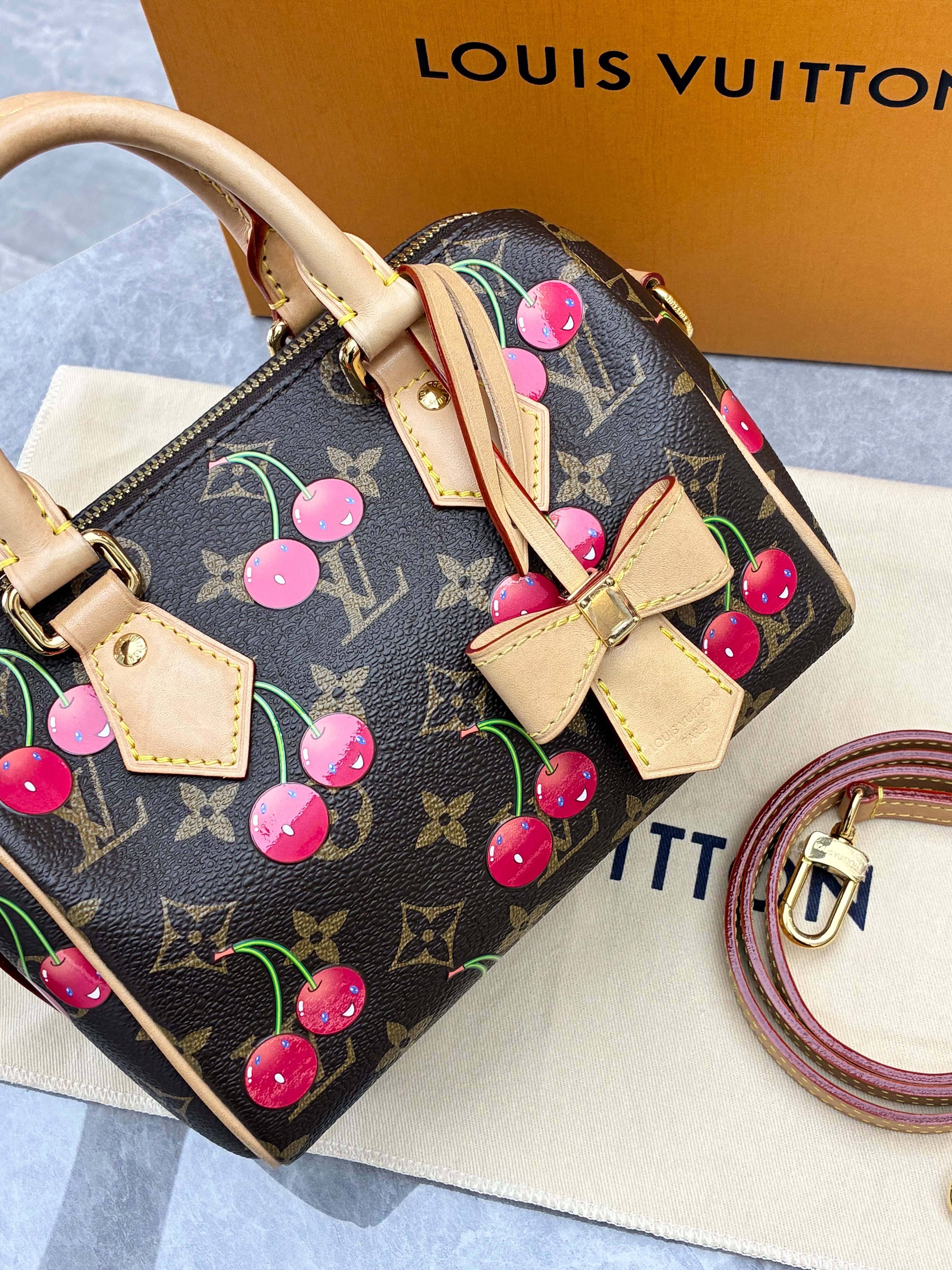 Louis Vuitton × Takashi Murakami Speedy Bandoulière 20 bag in monogram canvas features a playful cherry print and gold-tone hardware.