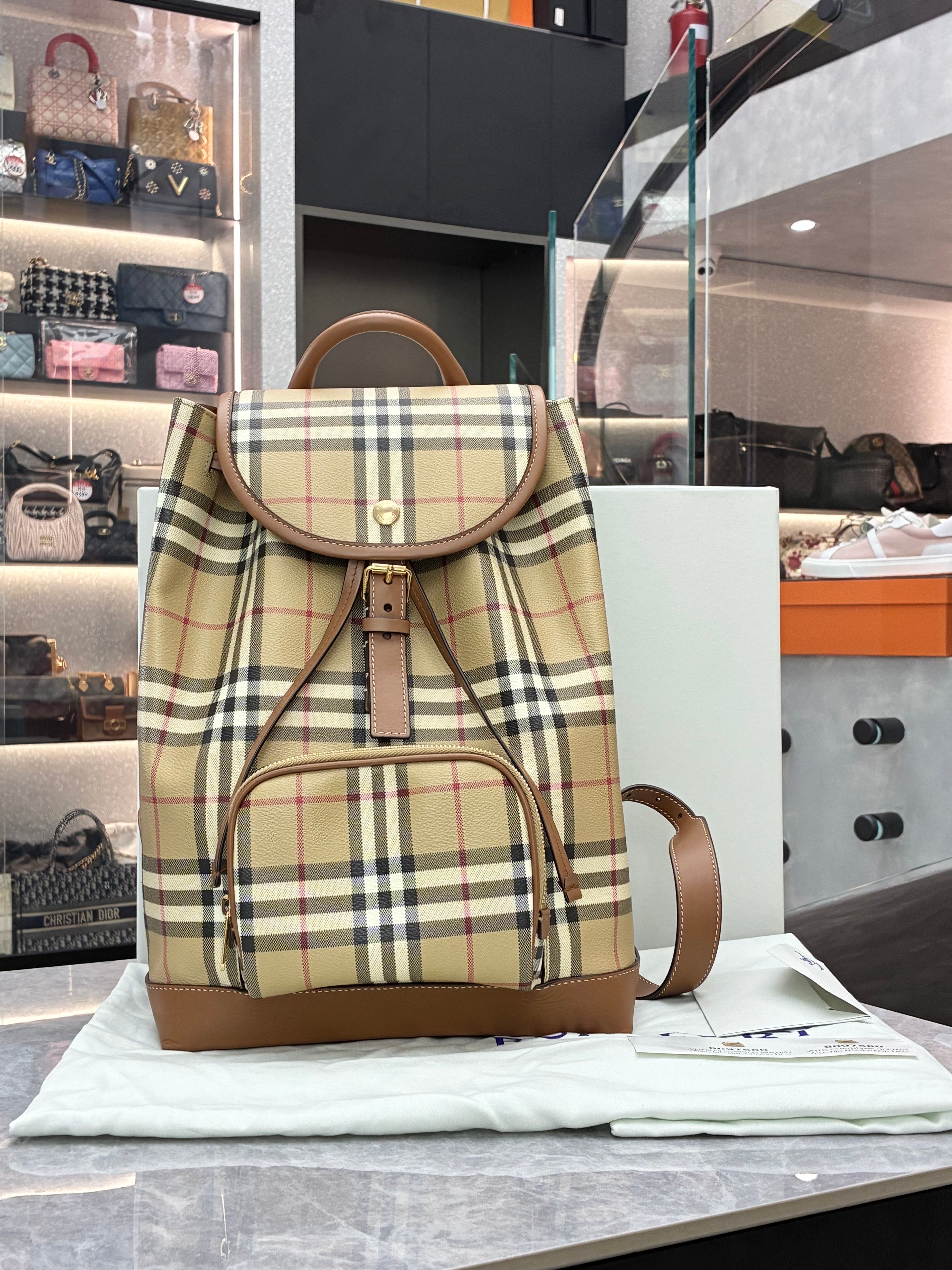 Burberry check drawstring backpack features the brand's iconic Heritage check pattern with brown leather trim, a front zip pocket, and polished gold-toned hardware