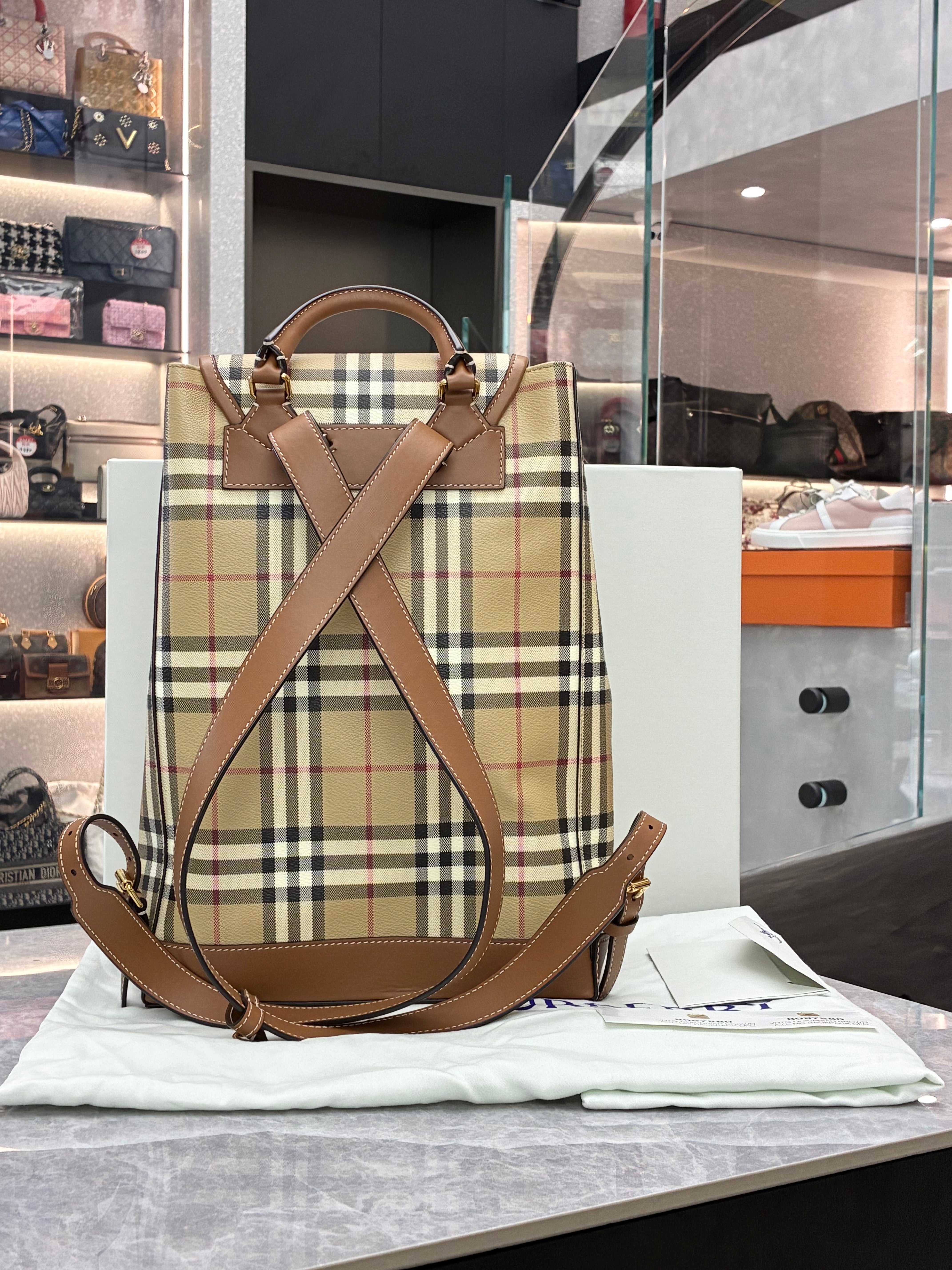 Burberry check drawstring backpack features the brand's iconic Heritage check pattern with brown leather trim, a front zip pocket, and polished gold-toned hardware
