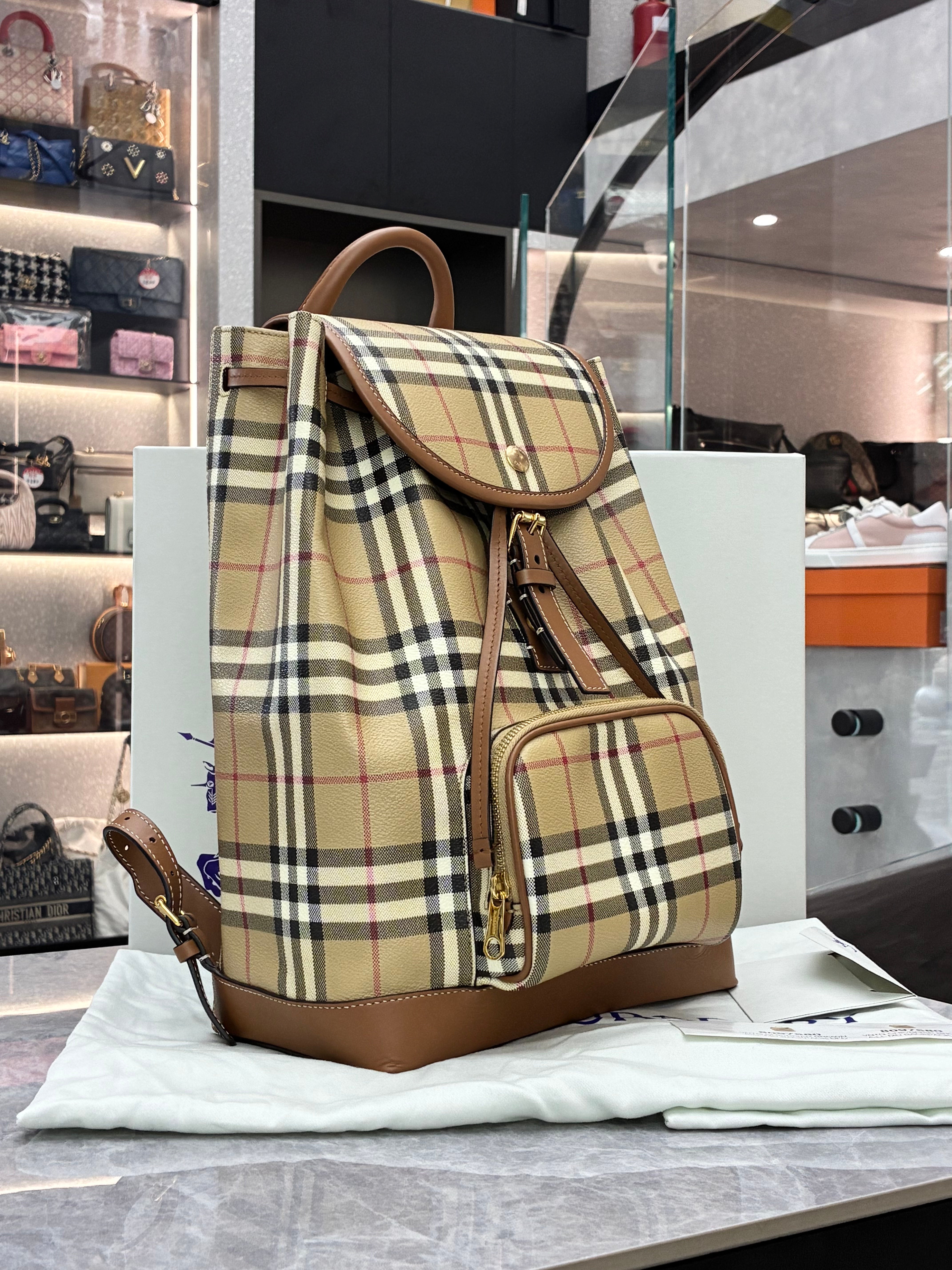 Burberry check drawstring backpack features the brand's iconic Heritage check pattern with brown leather trim, a front zip pocket, and polished gold-toned hardware