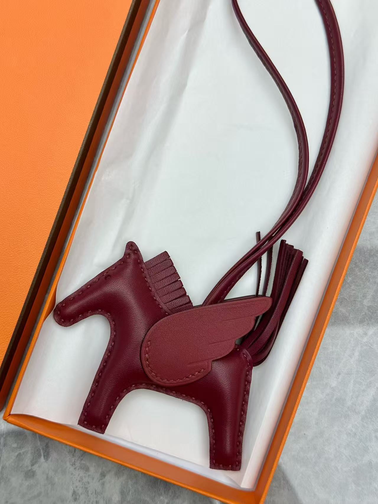 Hermès Rodeo Pegase PM bag charm in a burgundy color