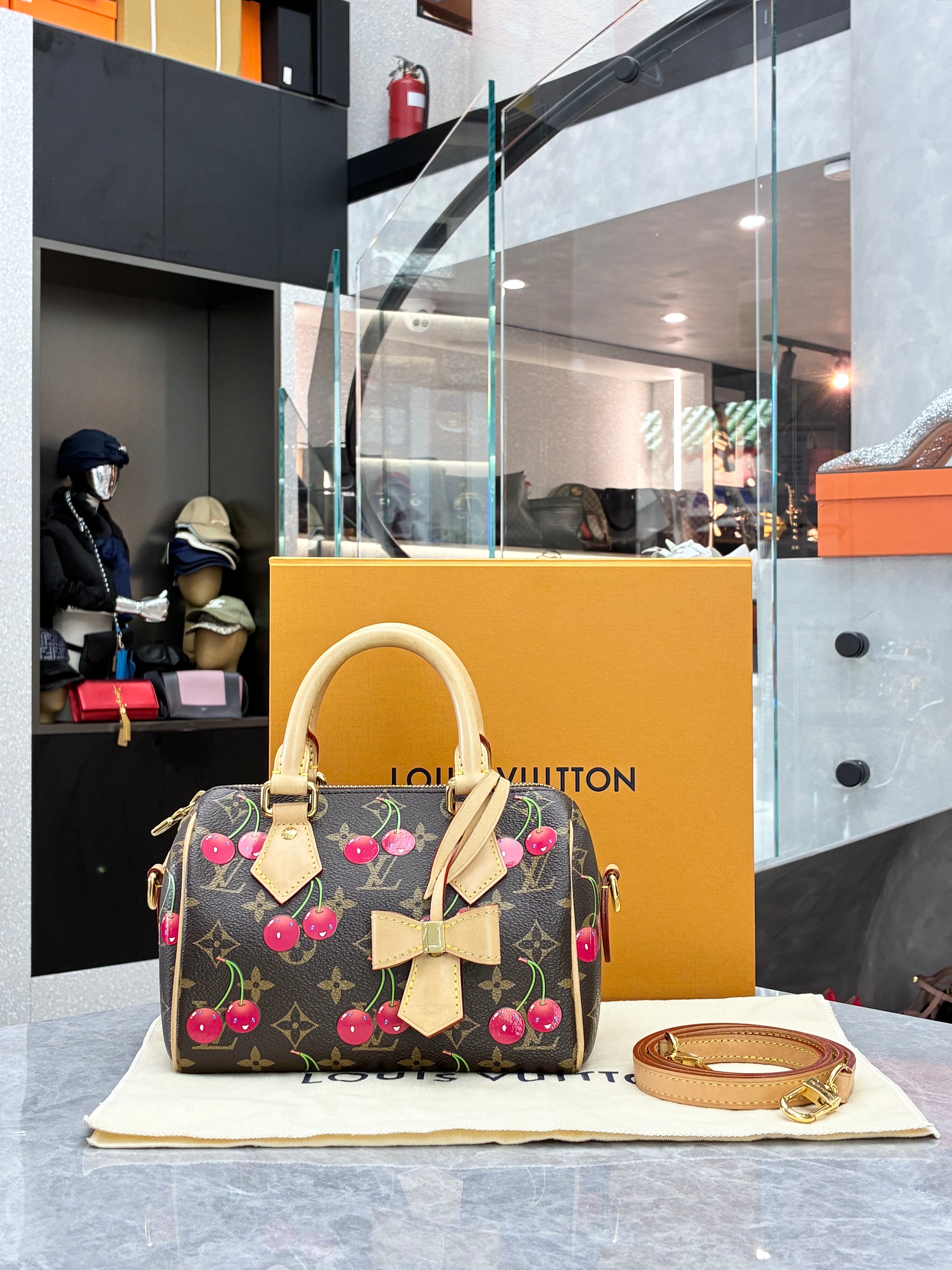 Louis Vuitton × Takashi Murakami Speedy Bandoulière 20 bag in monogram canvas features a playful cherry print and gold-tone hardware.
