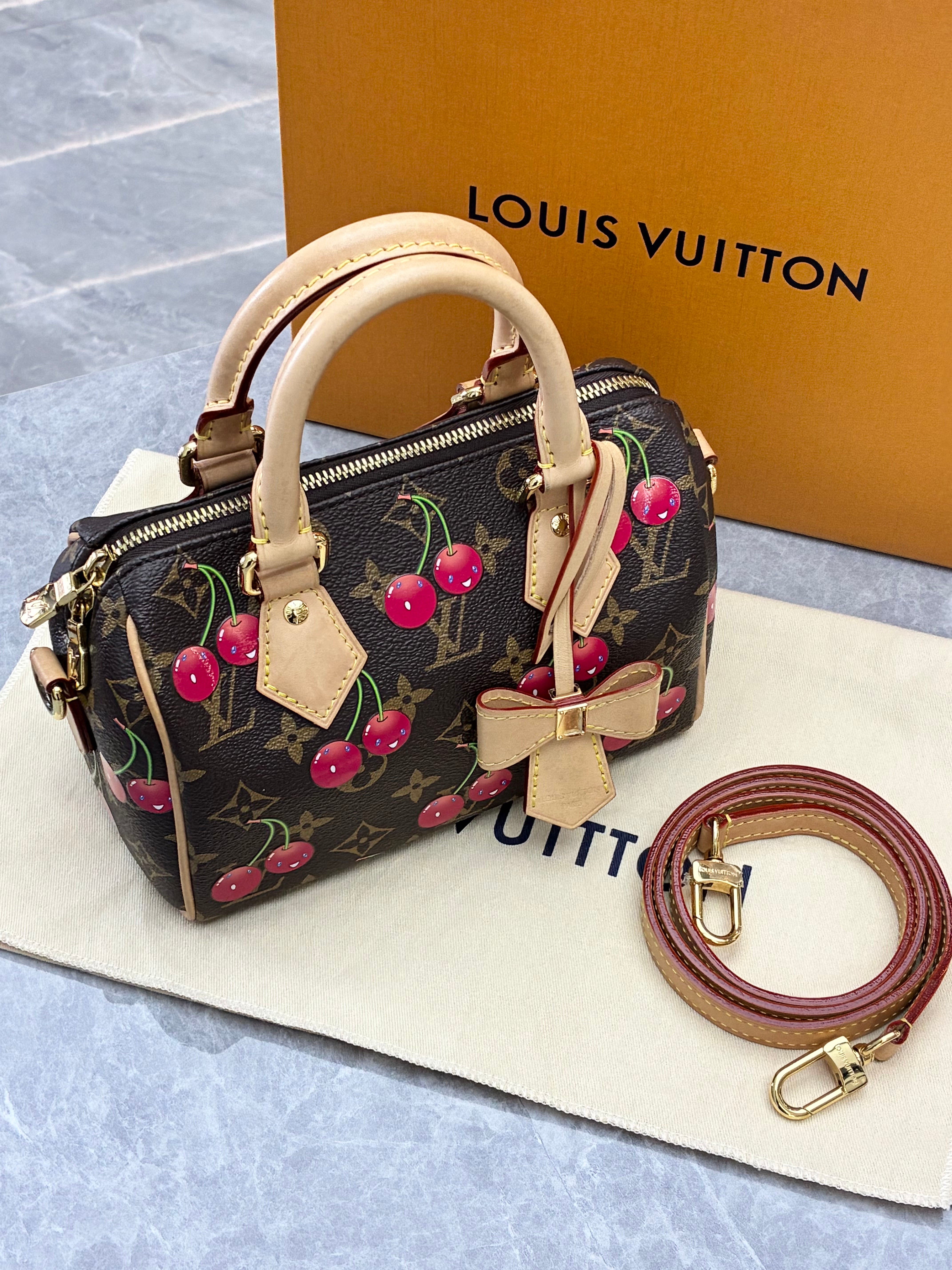 Louis Vuitton × Takashi Murakami Speedy Bandoulière 20 bag in monogram canvas features a playful cherry print and gold-tone hardware.